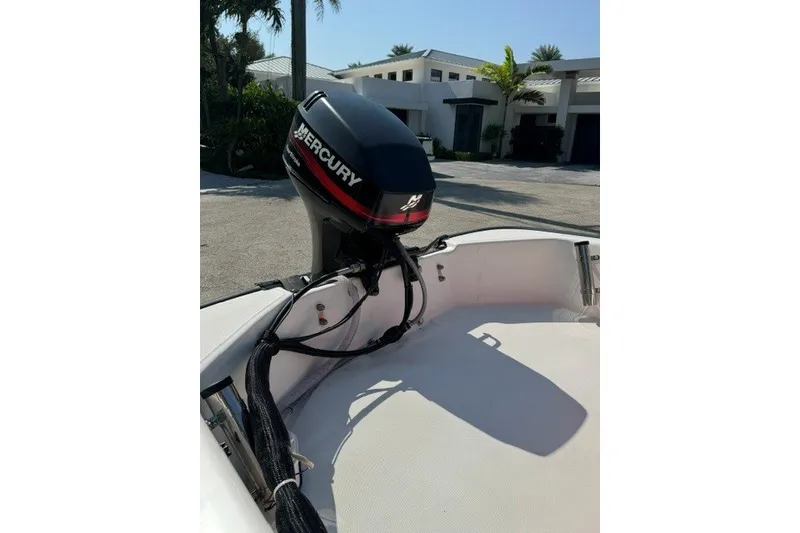 Slide: The Image of Boston Whaler Sport 13 boat with Mercury outboard motor, 2000 model, in a sunny driveway. - 13
