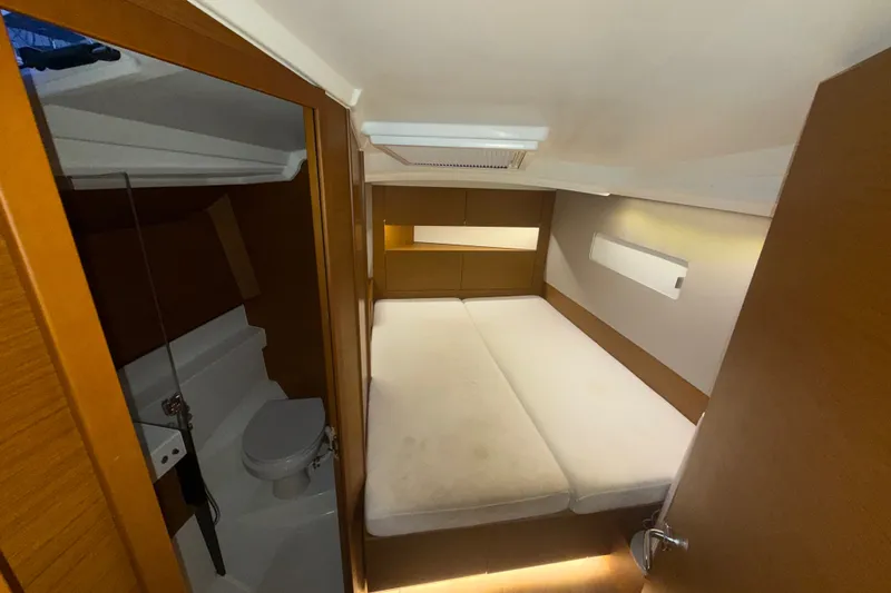 Slide: The Image of Interior cabin of 2022 Jeanneau Sun Odyssey 410 yacht, featuring a cozy bed and compact bathroom. - 38