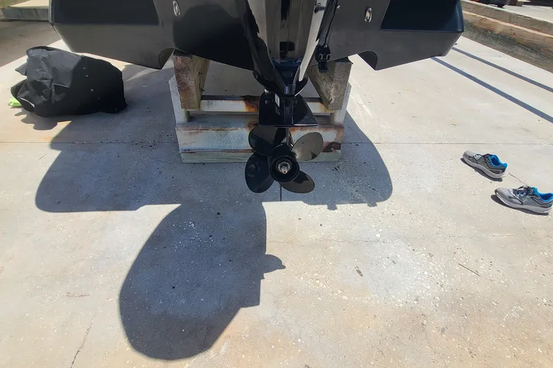 Slide: The Image of 2022 Bayliner Element M17 boat propeller on concrete with shoes nearby. - 17