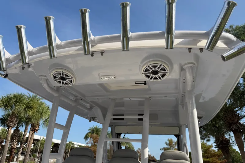 Slide: The Image of 2021 Everglades 335 Center Console boat with rod holders and speakers, under clear blue sky. - 23