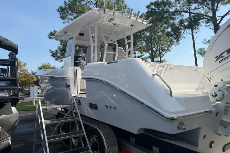 Slide: The Image of 2021 Everglades 335 Center Console boat on trailer, surrounded by trees. - 1