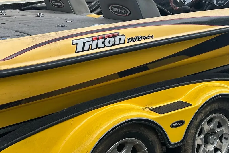 Slide: The Image of Yellow 2006 Triton 21 TrX boat with logo, featuring sleek design and trailer wheels. - 12