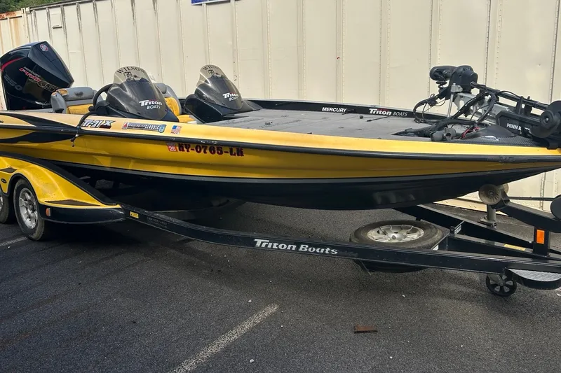 The Image of 2006 Triton 21 TrX yellow and black boat on trailer, parked outdoors. - 1