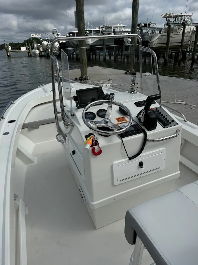 Slide: The Image of The image shows a 2023 Parker 1801 Center Console boat docked with a cloudy sky in the background. The helm features a steering wheel, a screen, and various controls. - 26