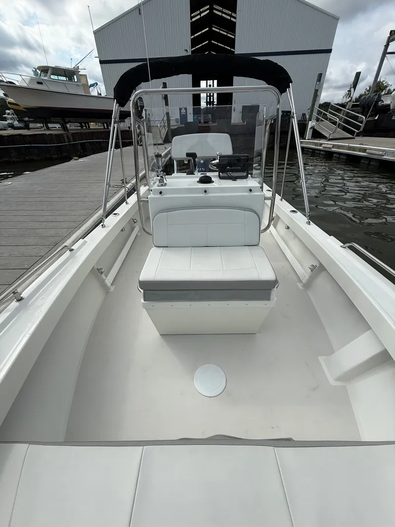 Slide: The Image of A 2023 Parker 1801 Center Console boat at a dock. It features a clean, white deck and protective canopy. - 20