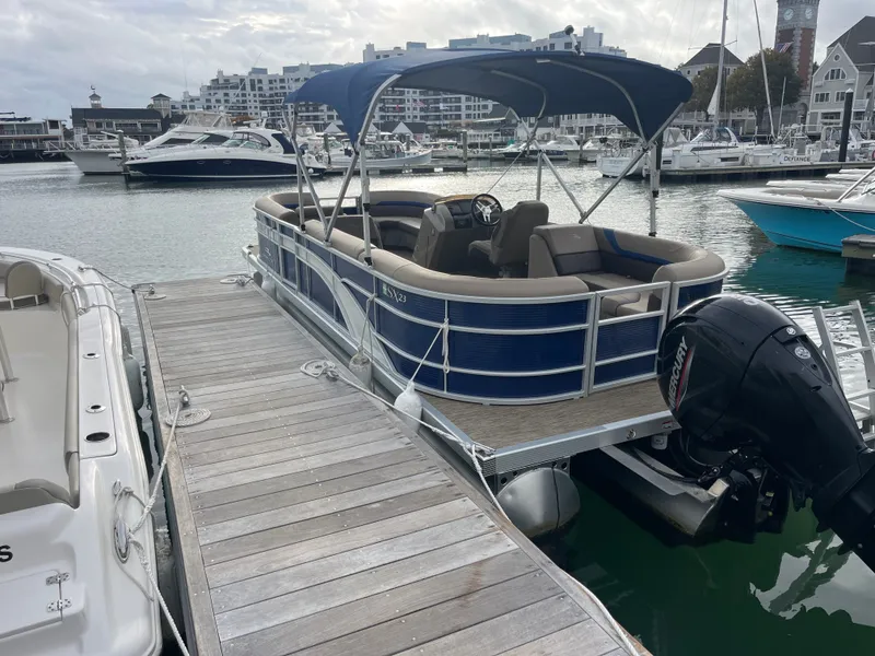 Slide: The Image of A 2022 Bennington 23SXSRC pontoon boat docked at a marina, featuring a blue canopy. - 3