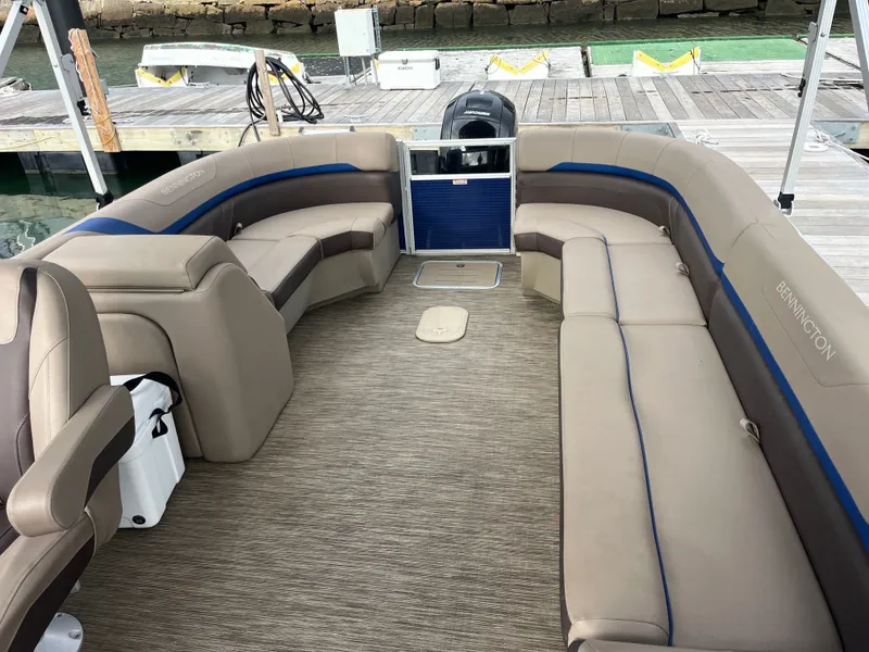 Slide: The Image of The image shows the spacious cockpit of a 2022 Bennington 23SXSRC pontoon boat with beige seating. - 10