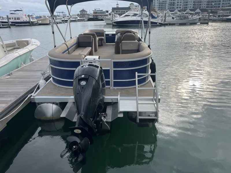 Slide: The Image of A 2022 Bennington 23SXSRC pontoon boat docked. It features an outboard motor and seating areas. - 2