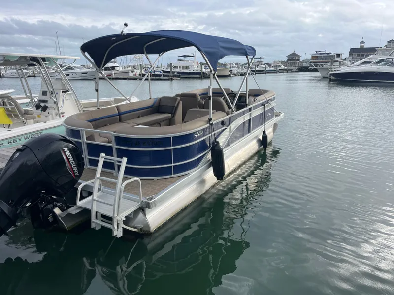 Slide: The Image of A 2022 Bennington 23SXSRC pontoon boat is docked. It features a blue canopy and outboard motor. - 1