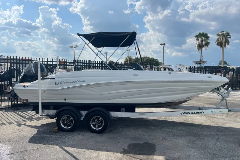 The Image of 2023 Crownline Eclipse E230 XS boat on trailer, parked outdoors under cloudy sky. - 0