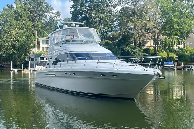 Slide: The Image of 2001 Sea Ray 560 Sedan Bridge yacht on a serene lake, surrounded by lush greenery. - 33