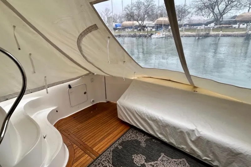 Slide: The Image of 2001 Sea Ray 560 Sedan Bridge interior with covered seating and wooden flooring. - 31
