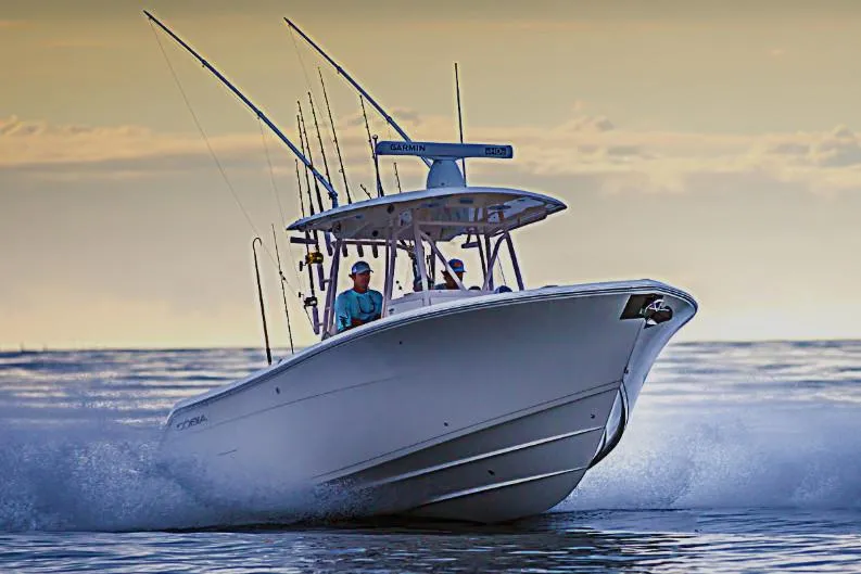 Slide: The Image of Manufacturer Provided Image: 2020 Cobia 301 Center Console boat cruising on the water at sunset. - 0