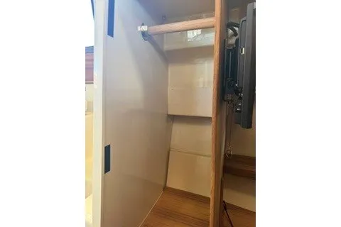 Slide: The Image of 2026 Ranger Tugs R-27 interior closet with wooden rod and shelving. - 15