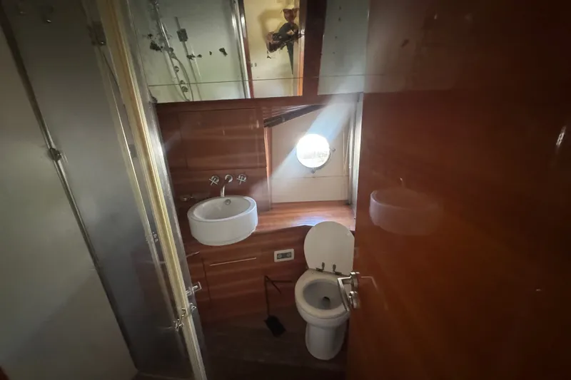 Slide: The Image of Luxurious bathroom interior on a 2007 Aicon 64 yacht, featuring wooden finishes and a porthole window. - 17