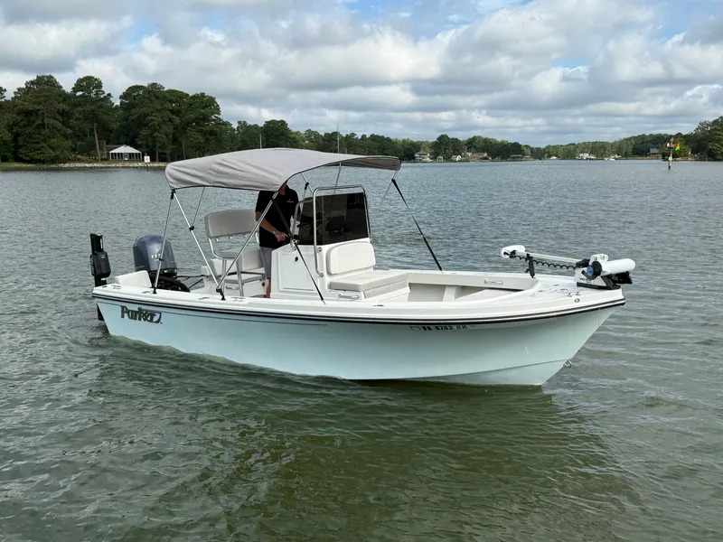 The Image of 2021 Parker 1801 Center Console on calm water, featuring a Bimini top and outboard motor. - 0