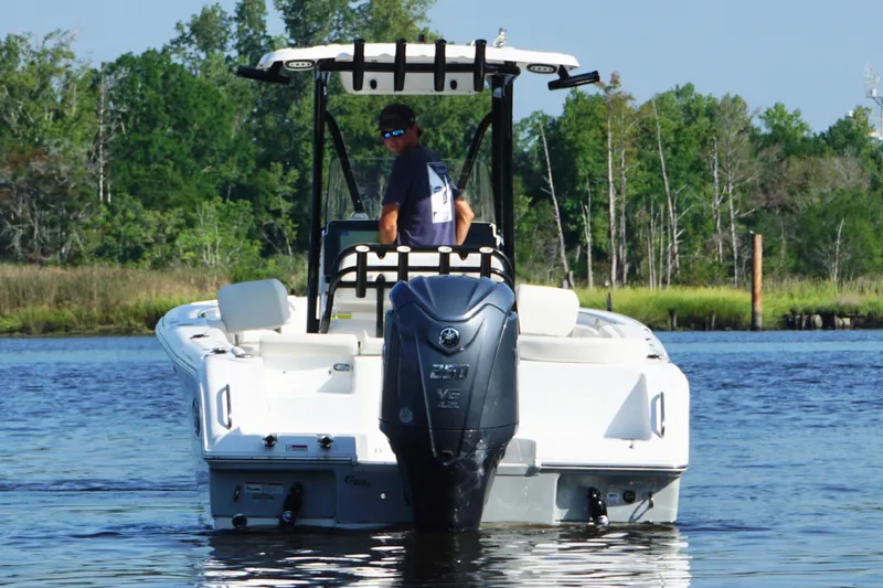 Slide: The Image of 2022 Sea Hunt Ultra 234 boat cruising on a calm river with lush greenery. - 7