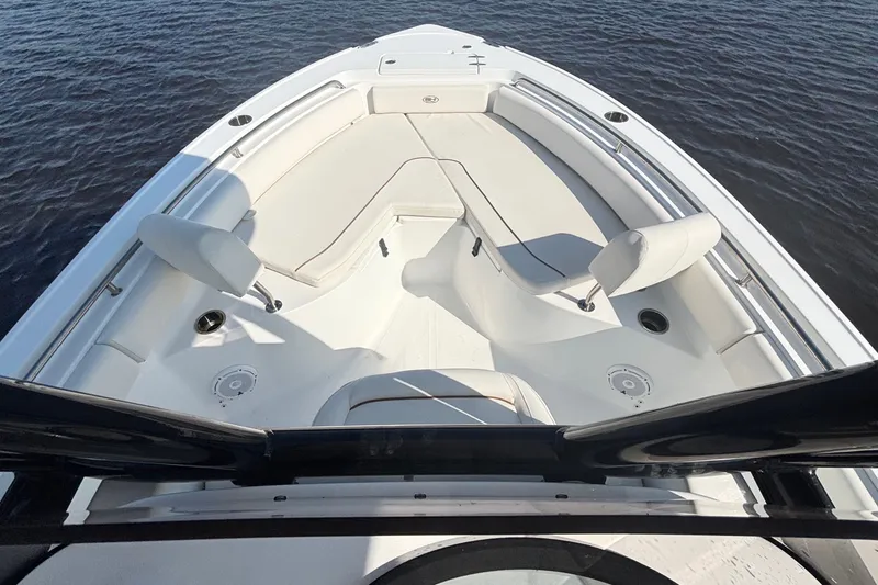 Slide: The Image of 2022 Sea Hunt Ultra 234 boat interior with white seating, on calm water. - 12
