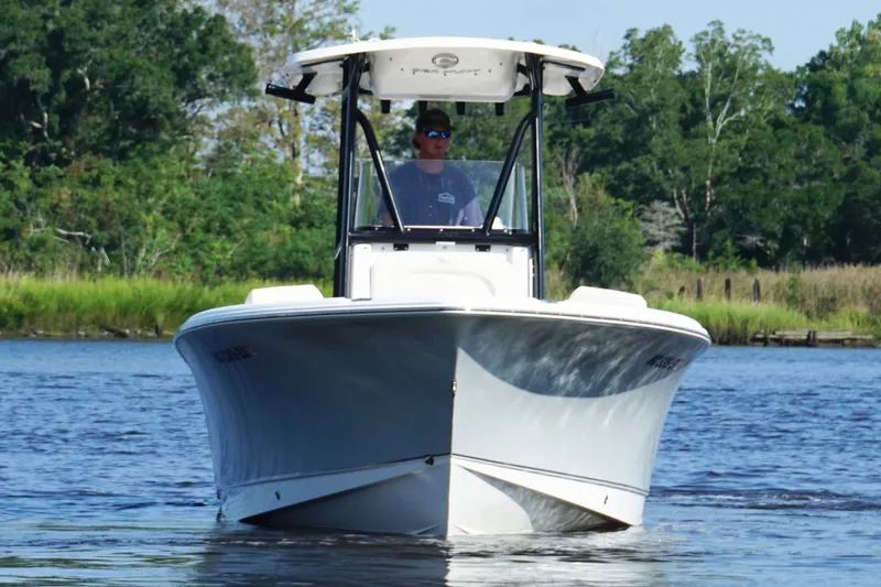 Slide: The Image of 2022 Sea Hunt Ultra 234 boat cruising on a calm river with lush greenery. - 6
