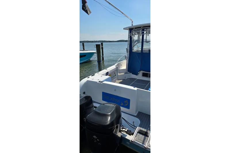 Slide: The Image of 2004 PROLINE 30 Express Walk boat docked by the water, featuring dual outboard motors. - 3