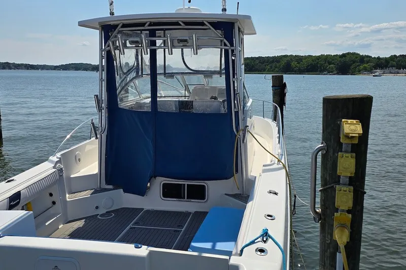 Slide: The Image of 2004 PROLINE 30 Express Walk boat docked by the water, featuring a blue canopy. - 1