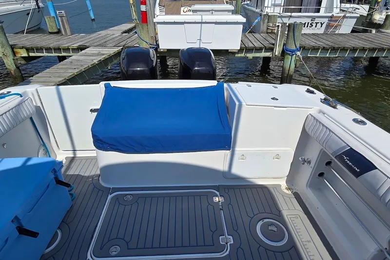 Slide: The Image of 2004 PROLINE 30 Express Walk boat deck with blue seating and twin engines at dock. - 5