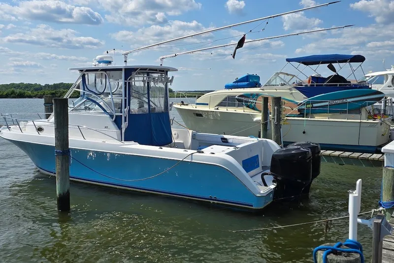 The Image of 2004 PROLINE 30 Express Walk boat docked in a marina under a partly cloudy sky. - 0