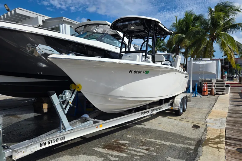 The Image of 2025 Sea Pro 225FLX Sandbar boat on trailer, dockside with palm trees. - 0