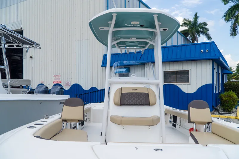 Slide: The Image of 2021 Tidewater 2300 Carolina Bay boat with seating, docked near a blue and white building. - 13