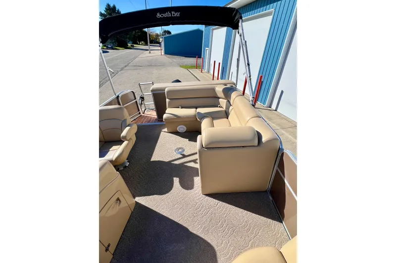 Slide: The Image of 2013 South Bay 417 CR pontoon boat with beige seating and canopy, docked near blue building. - 40