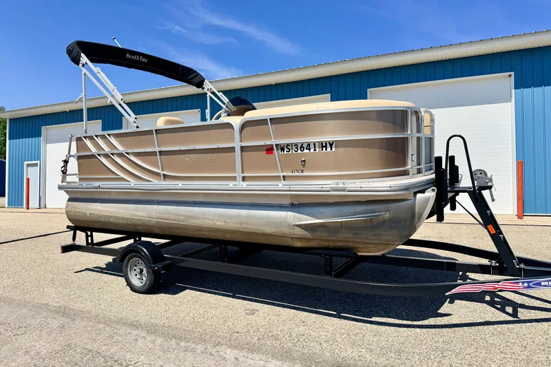 Slide: The Image of 2013 South Bay 417 CR pontoon boat on trailer, parked outside blue building. - 4