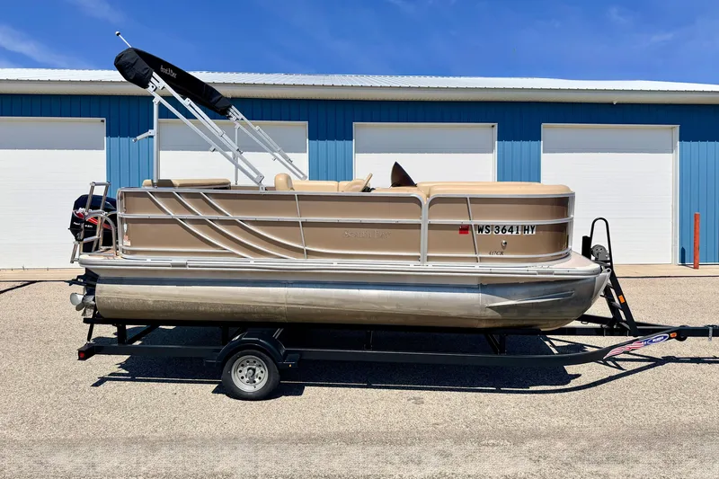 Slide: The Image of 2013 South Bay 417 CR pontoon boat on trailer, parked near blue building. - 2