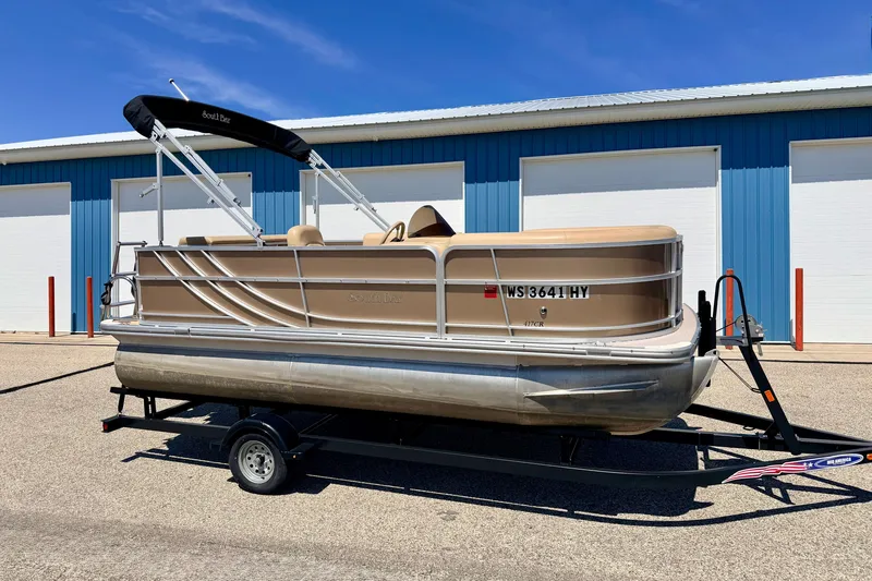 The Image of 2013 South Bay 417 CR pontoon boat on trailer, parked near blue building. - 0