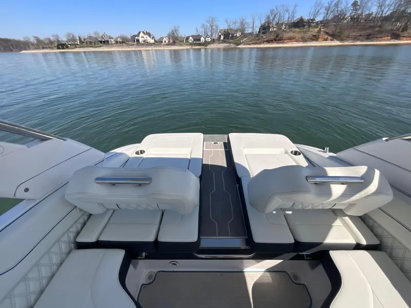 Slide: The Image of 2023 Regal LS6 boat with luxurious seating, overlooking a serene lake view. - 14