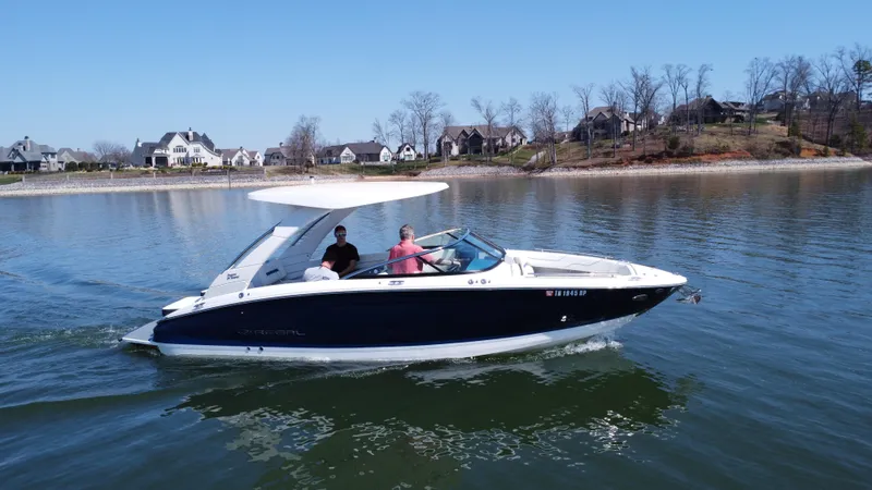 The Image of 2023 Regal LS6 boat cruising on a lake with passengers, near a residential shoreline. - 0