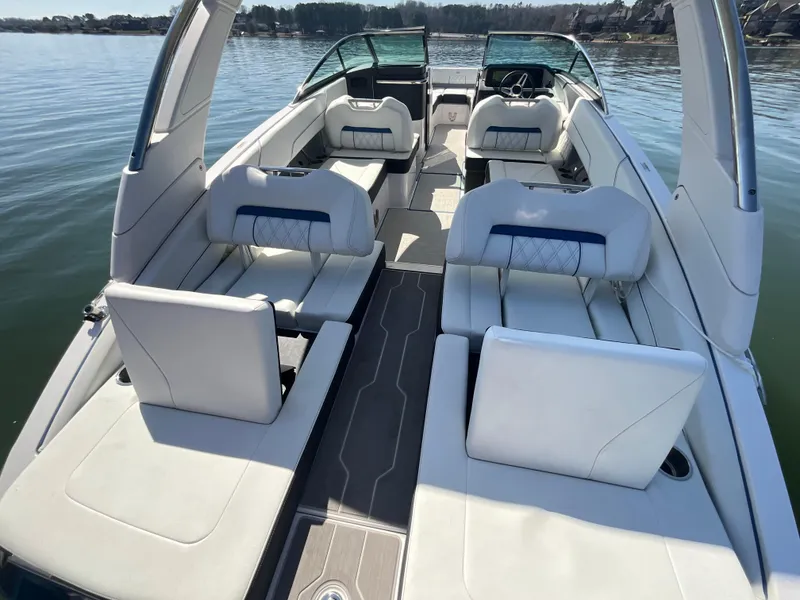 Slide: The Image of 2023 Regal LS6 boat interior with luxurious seating on a calm lake. - 19