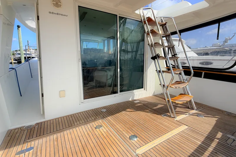 Slide: The Image of 2006 Beneteau Swift Trawler 42 with wooden deck and metal ladder in marina setting. - 17