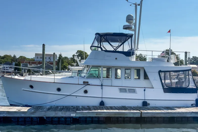 The Image of A 2006 Beneteau Swift Trawler 42 docked, featuring a blue canopy and classic design. - 0