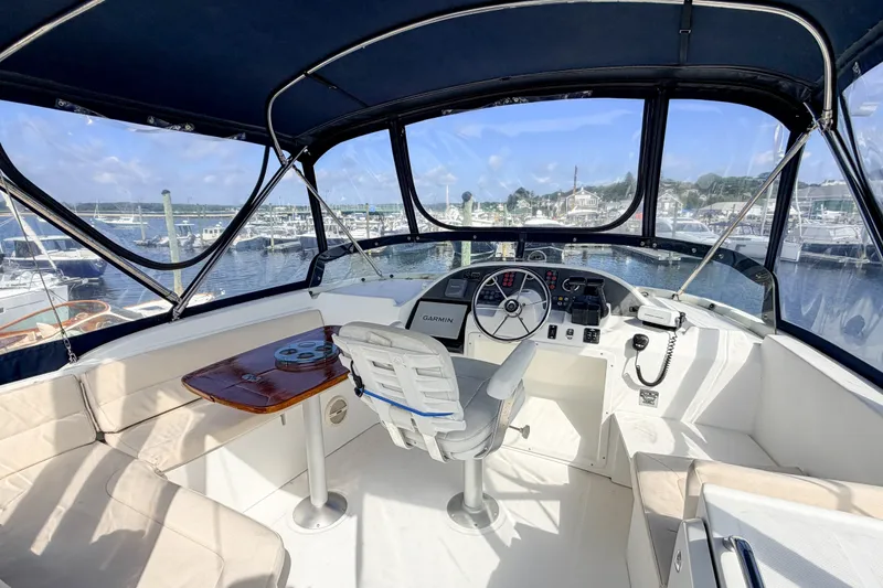 Slide: The Image of 2006 Beneteau Swift Trawler 42 helm with marina view, featuring navigation equipment and seating. - 24