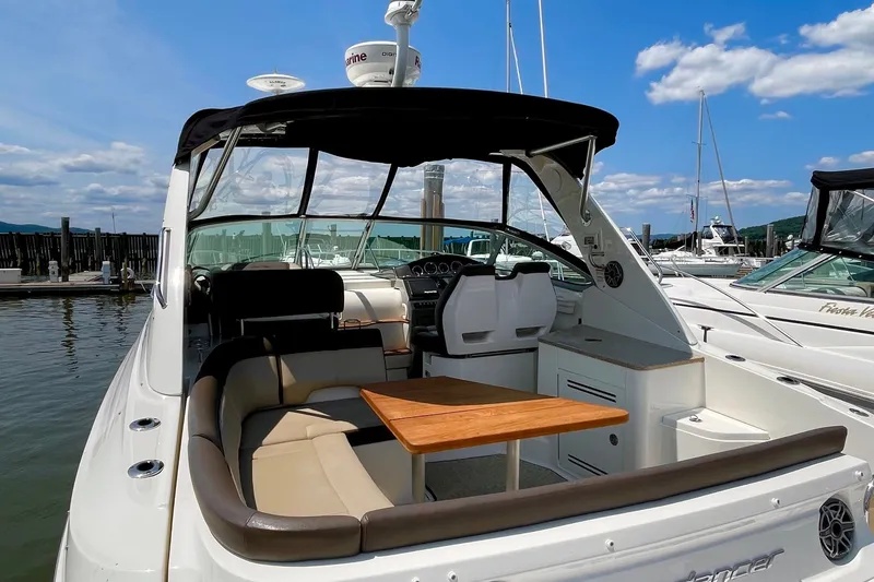 Slide: The Image of 2015 Sea Ray Sundancer 350 yacht with seating and table, docked under a clear sky. - 17