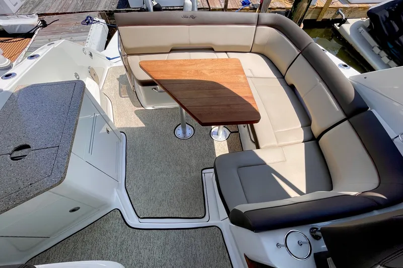 Slide: The Image of 2015 Sea Ray Sundancer 350 boat interior with cushioned seating and wooden table. - 16