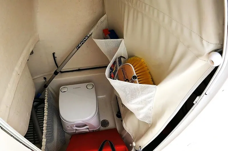 Slide: The Image of Storage compartment in a 2018 Key West 239 FS boat with cleaning supplies and portable toilet. - 18