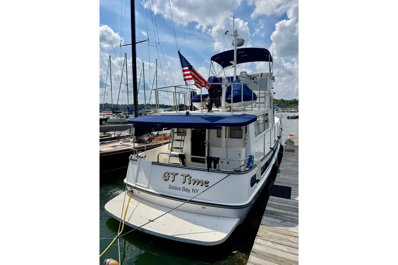 Slide: The Image of 2016 Nordic Tug 44 docked at Sodus Bay, NY, featuring blue canopy and American flag. - 4