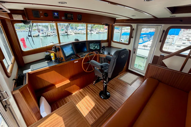 Slide: The Image of Interior of 2016 Nordic Tug 44 boat, featuring helm station and marina view. - 46