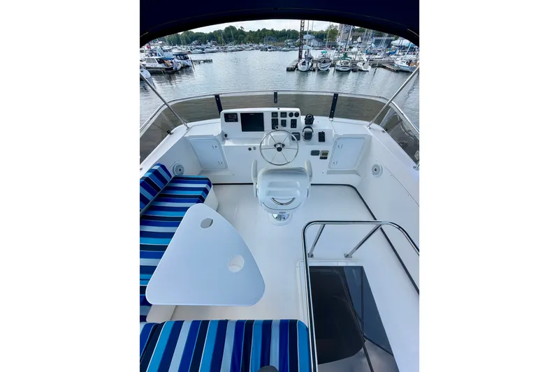 Slide: The Image of Flybridge of 2016 Nordic Tug 44 with striped seating, helm, and marina view. - 24