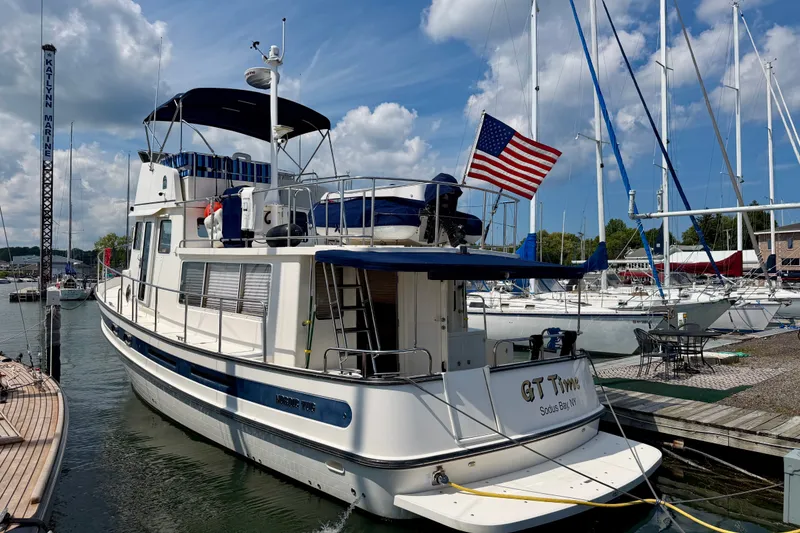 Slide: The Image of 2016 Nordic Tug 44 docked at marina, featuring American flag and clear blue sky. - 3