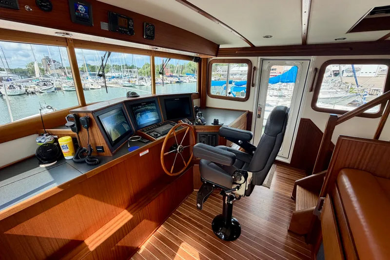 Slide: The Image of Pilothouse of 2016 Nordic Tug 44 with helm, navigation screens, and marina view. - 47