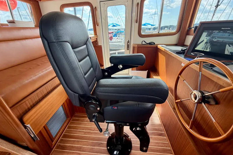 Slide: The Image of Pilot seat and helm in 2016 Nordic Tug 44 boat interior, featuring wood accents and navigation equipment. - 48