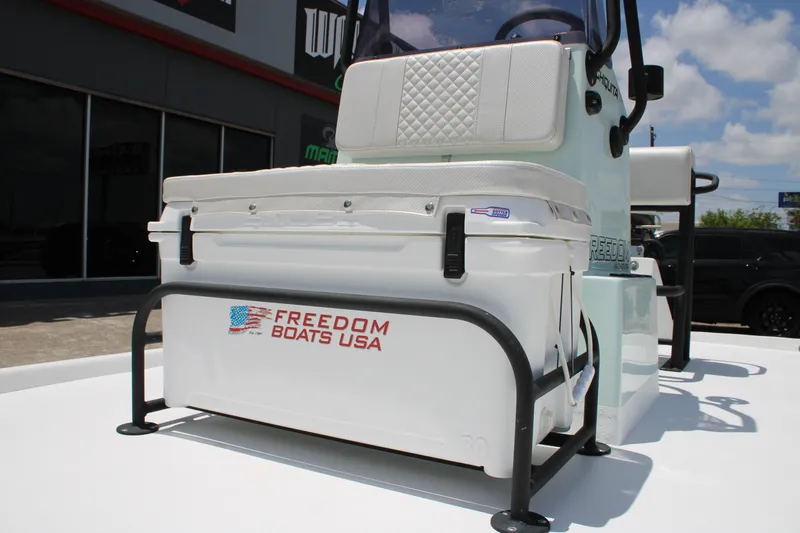 Slide: The Image of 2027 Freedom Boats Chiquita with cushioned seating and storage, displayed outdoors. - 14
