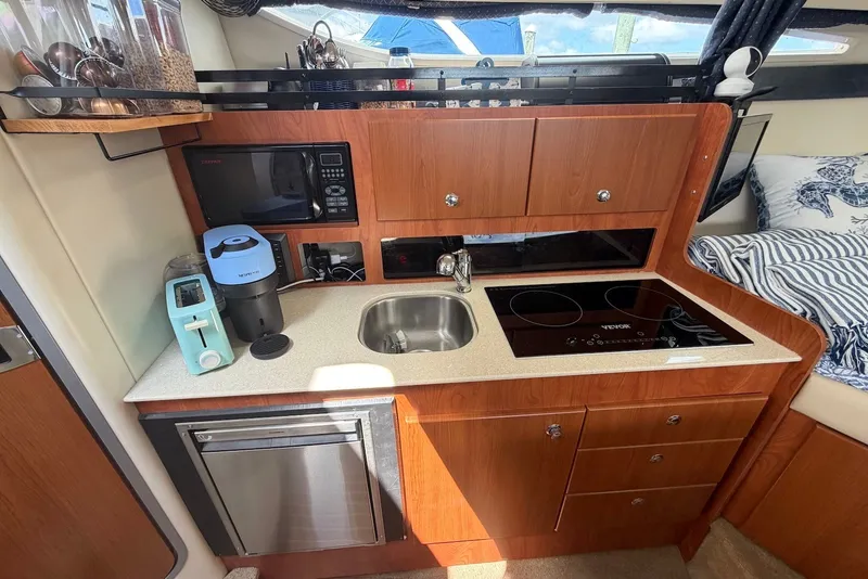 Slide: The Image of 2008 Bayliner 300 boat kitchen with sink, stove, microwave, and appliances. - 14